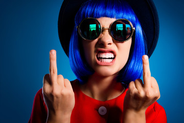 Closeup cropped portrait of nervous annoyed woman in wig eyewear showing teeth gesturing two fuck...