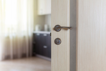 Naklejka premium Wooden door with metallic handle open in to the empty kitchen