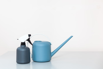 The watering can and sprayer are on the table on a light background