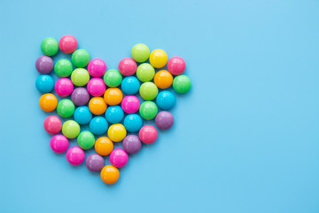 Sweet candy heart shape onblue background. Love dessert concept with copy space