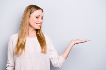 Portrait with empty place of positive pretty girl looking at copy space on palm isolated on grey background