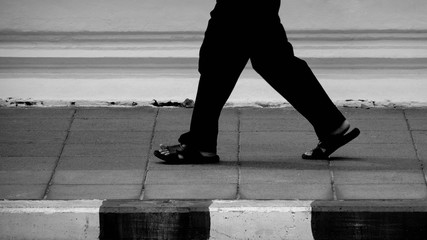 lonely man walk on a pavement in the urban - monochrome