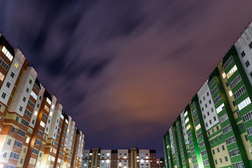 View of apartment buildings under dark night sky and long exposure blue-white-and-orange clouds in Russia. City of Barnaul, Siberia.