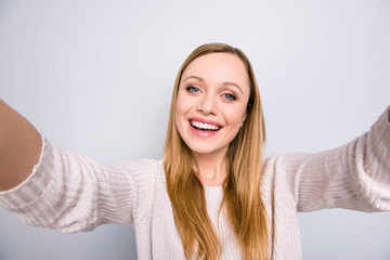Self portrait of pretty positive girl shooting selfie on front camera with two hands having video-call with friend isolated on grey background