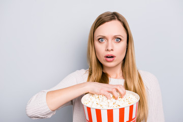 Naklejka premium Portrait of shocked astonished girl with wide open eyes mouth holding bucket with pop corn looking exciting interesting premier horror film isolated on grey background