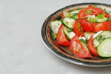 Tomato and cucumber salad with black pepper vegan food with fork gray textured cement background