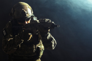 Special forces soldier with rifle on dark background
