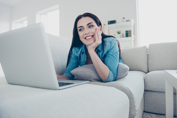 Fototapeta premium Portrait of cheerful pretty customer attractive woman lying on stomach on sofa pillow using laptop for online shopping searching movie film enjoying domestic lifestyle