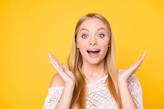 Portrait of delightful satisfied girl gesturing with palms looking at camera with wide open mouth eyes isolated on yellow background