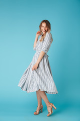 Full length image of Laughing blonde woman in dress dancing
