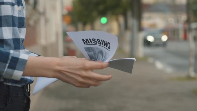 Girl handing out leaflets about the missing child,close up