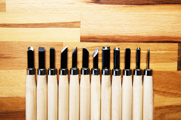 a set of different tools for cutting wood products, with a wooden handle on a wooden Board background