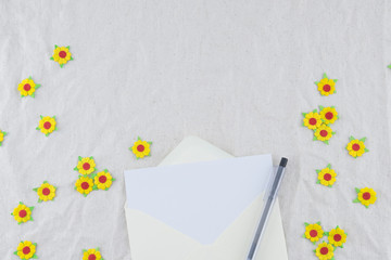 White card in yellow envelop with black pen decorate with yellow paper flowers on muslin fabric...