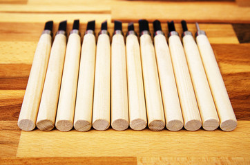 a set of different tools for cutting wood products, with a wooden handle on a wooden Board background