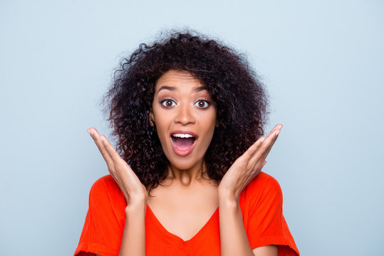 Portrait of surprised amazed woman with modern hairdo bright outfit keeping wide open mouth eyes gesturing with palms looking at camera isolated on grey background