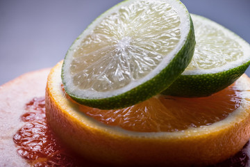 Citrus summer background. Pyramid of lime, orange, grapefruit slices on grey background close up.