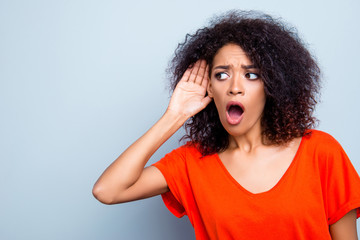 Portrait with copy space of shocked worried woman with wide open mouth holding hand near ear listening bad information gossips isolated on grey background