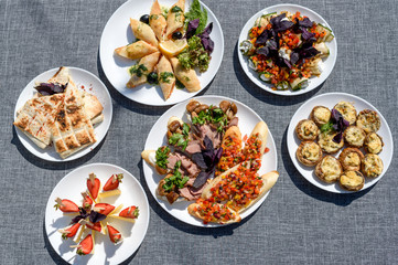 Plates with snacks on servered buffet table at wedding reception outdoors, copy space. Grilled mushrooms with cheese. Sandwiches, appetizer bruschetta, antipast, crostini, tapas. top view, flat lay