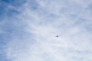 Small plane in the blue sky with clouds. Airplane flies high in the sky to the clouds.