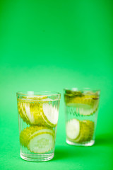 Nutritious fresh homemade detox water from organic cucumbers in a glass against a green background