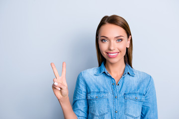 Portrait of  nice cute girl in casual outfit jeans shirt showing v-sign having beaming smile, standing over grey background