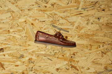 Men brown leather boats shoes, or topsiders on a yellow and brown wooden background. Fashion...