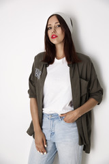 Fototapeta premium Fashionable, swarthy girl in a white T-shirt, shirt and jeans isolated on a red background.