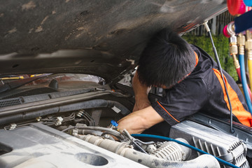 Maintenance checking car engine and using Manifolds Gauge air conditioning in auto vehicle fill refrigerant in car garage.