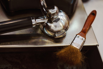 Portafilter and clean blush on stainless Knock box in coffee shop.