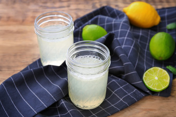 Glass jars with delicious citrus juice and fresh fruits on table