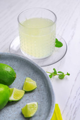 Glass with delicious citrus juice and fresh lime on table