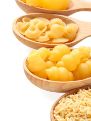 Wooden spoons with different types of pasta on white background