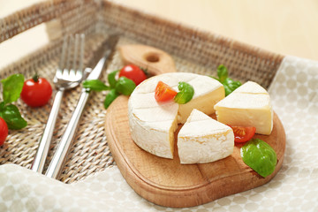 Delicious brie cheese with basil and cherry tomatoes on tray