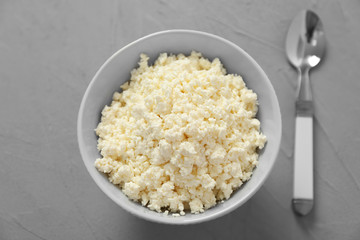 Bowl with tasty cottage cheese on grey table