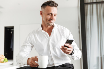 Smiling man dressed in formal clothes having breakfast
