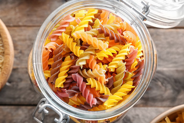 Jar with uncooked pasta on table