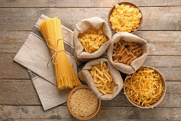 Different uncooked pasta on wooden background