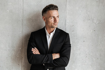 Handsome man dressed in suit holding arms folded