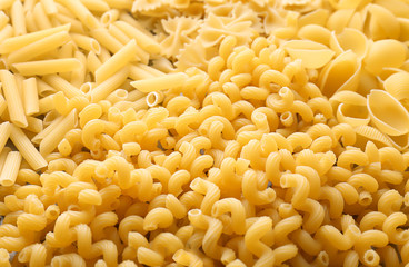 Different uncooked pasta as background, closeup