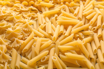 Different uncooked pasta as background, closeup