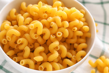 Bowl with uncooked pasta on table, closeup
