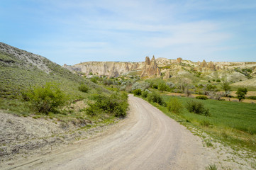 front view of road in valley and mountains under cloudy blue sky, Cappadocia, Turkey
