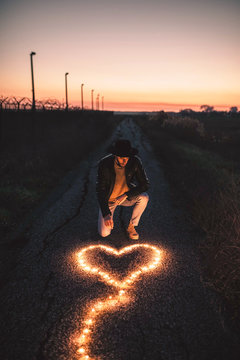 Simbolo del cuore ai piedi di un ragazzo in una strada al tramonto fatto con una striscia luminosa led.
