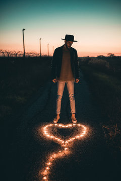 Simbolo del cuore ai piedi di un ragazzo in una strada al tramonto fatto con una striscia luminosa led.