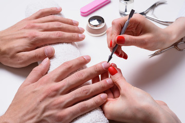 Men's manicure. hands of the beautician treated cuticle of male hands using pusher, scraper