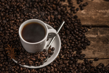 Cup of coffee with coffee beans and grinder on wooden table