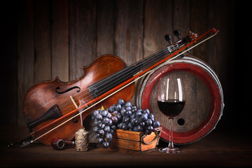 Composition with red grape, wine, violin and barrel