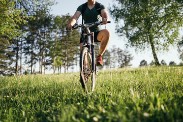 Obraz premium Detail of cyclist man feet riding mountain bike on outdoor trail deep grass