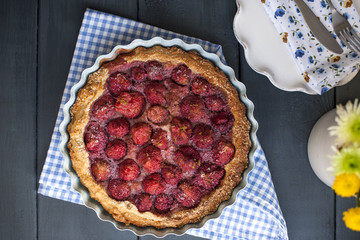 Open cake with strawberries in blue bowl for breakfast, on a black wooden background. Homemade baking. Free space for text. Copy space . Flat lay