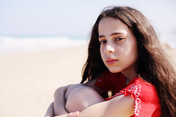 Portrait of aborable 12 years old girl walking alone on the beach in summer day